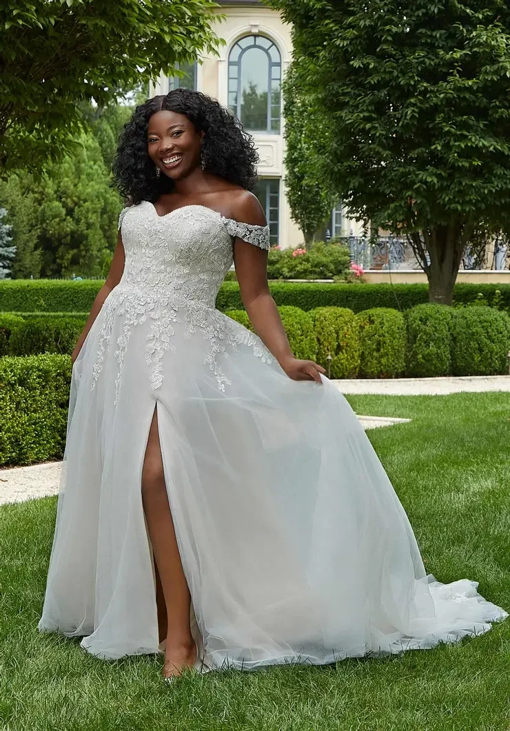 model is wearing an off the shoulder a-line plus size bridal gown