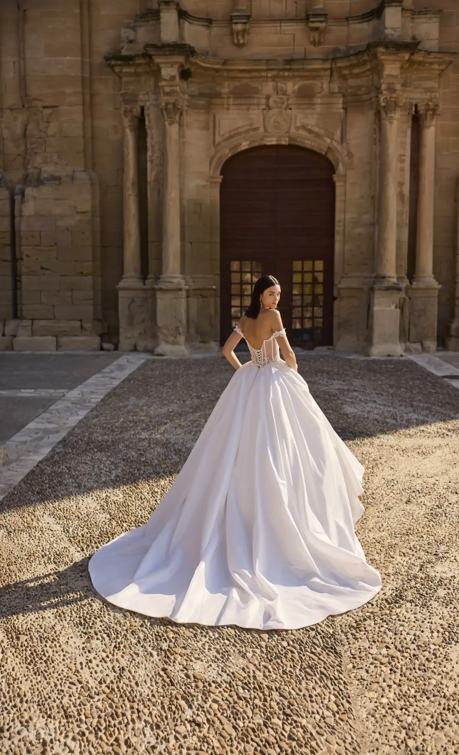 model is wearing an off the shoulder ball gown bridal dress