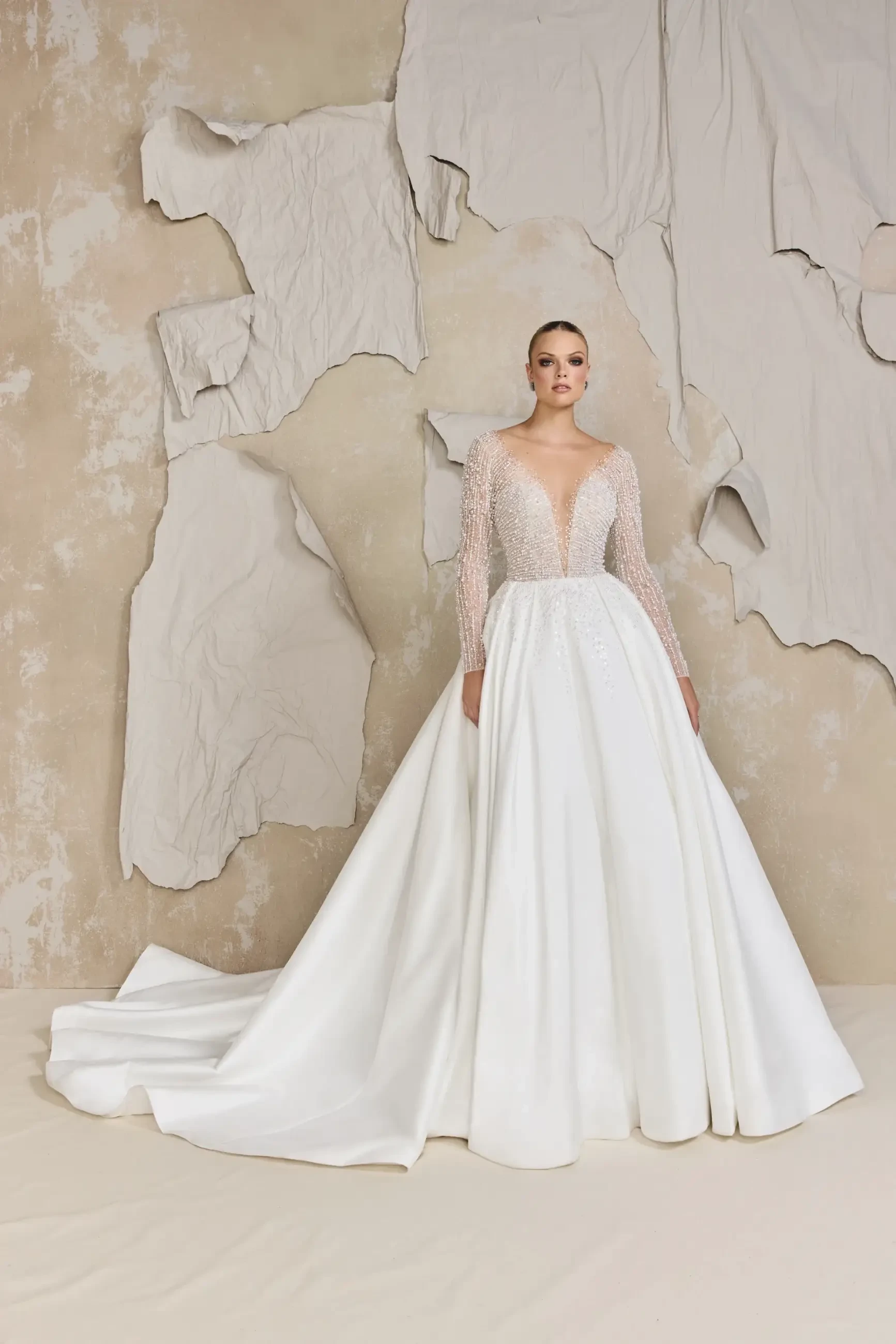 model is wearing a long sleeve ball gown wedding dress