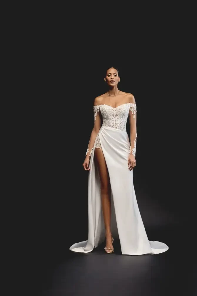 A sleek fit-and-flare gown featuring an illusion bodice, high slit, and open back for a bold yet elegant bridal look.