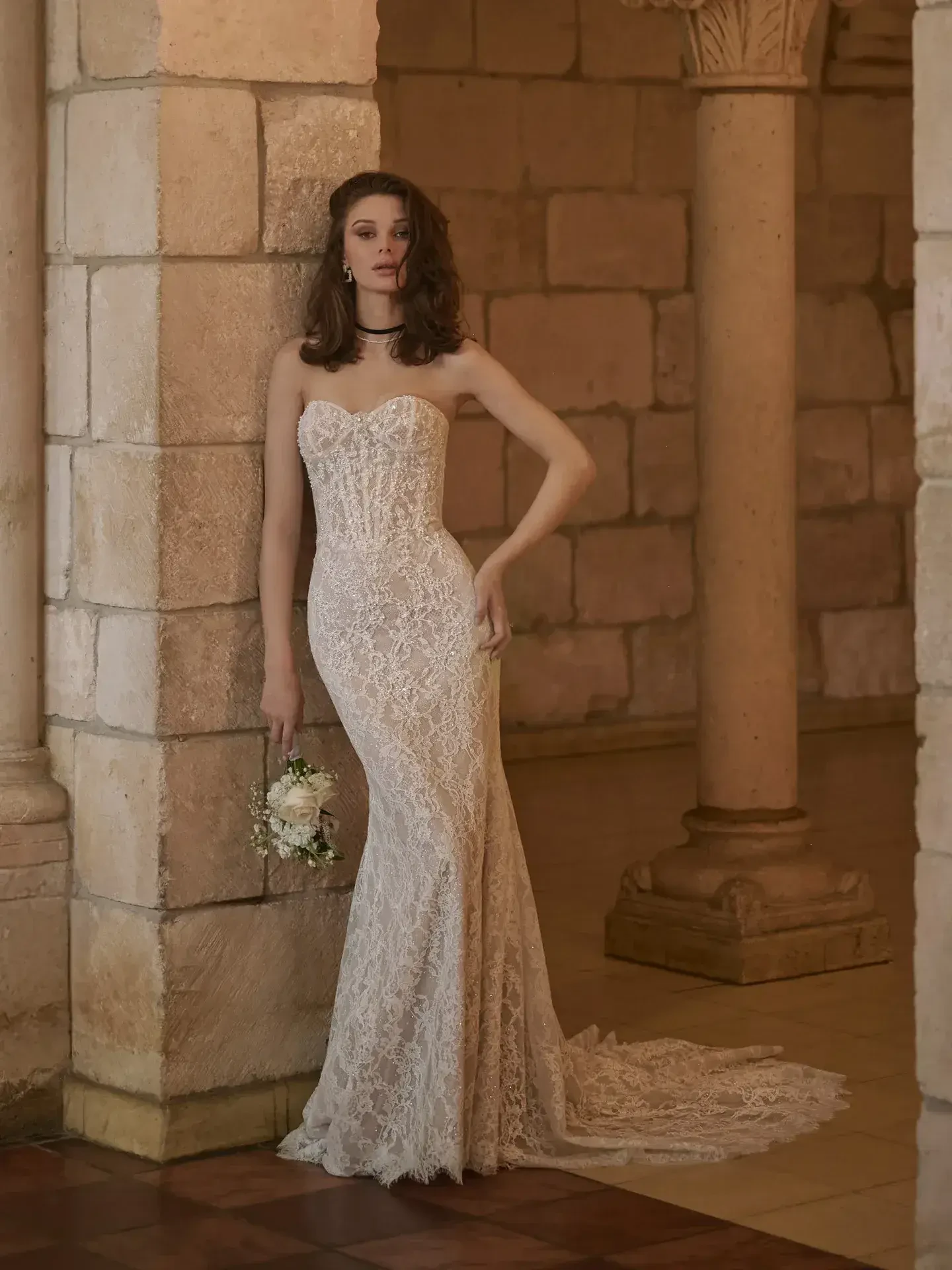model is wearing a strapless lace fit and flare bridal gown