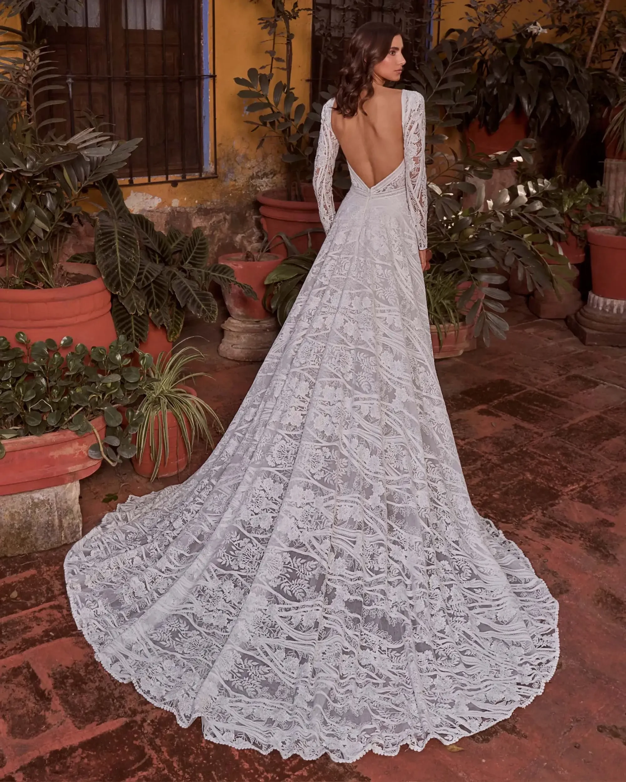 A romantic A-line gown with long lace sleeves, a plunging neckline, and a dramatic open back.