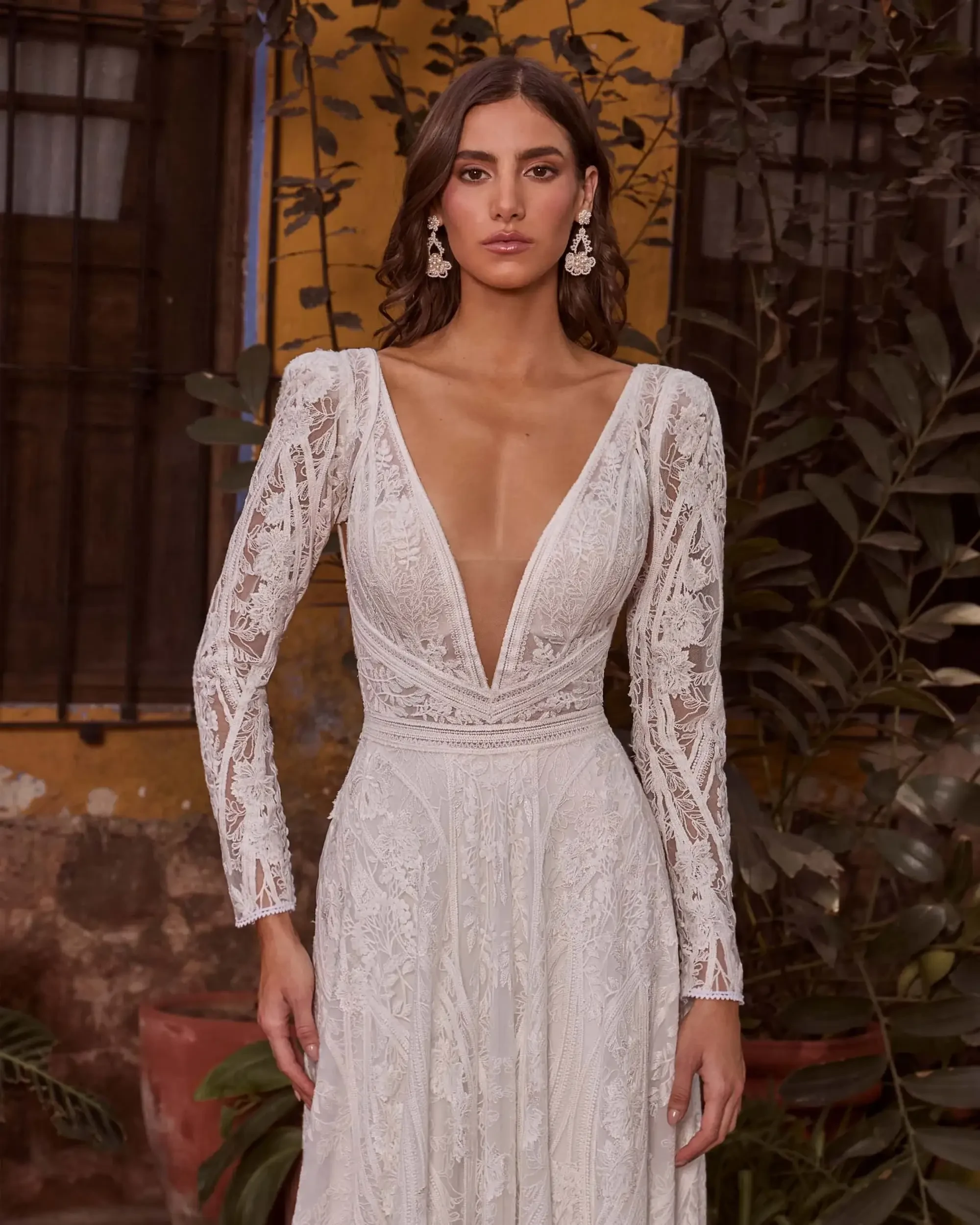 A romantic A-line gown with long lace sleeves, a plunging neckline, and a dramatic open back.