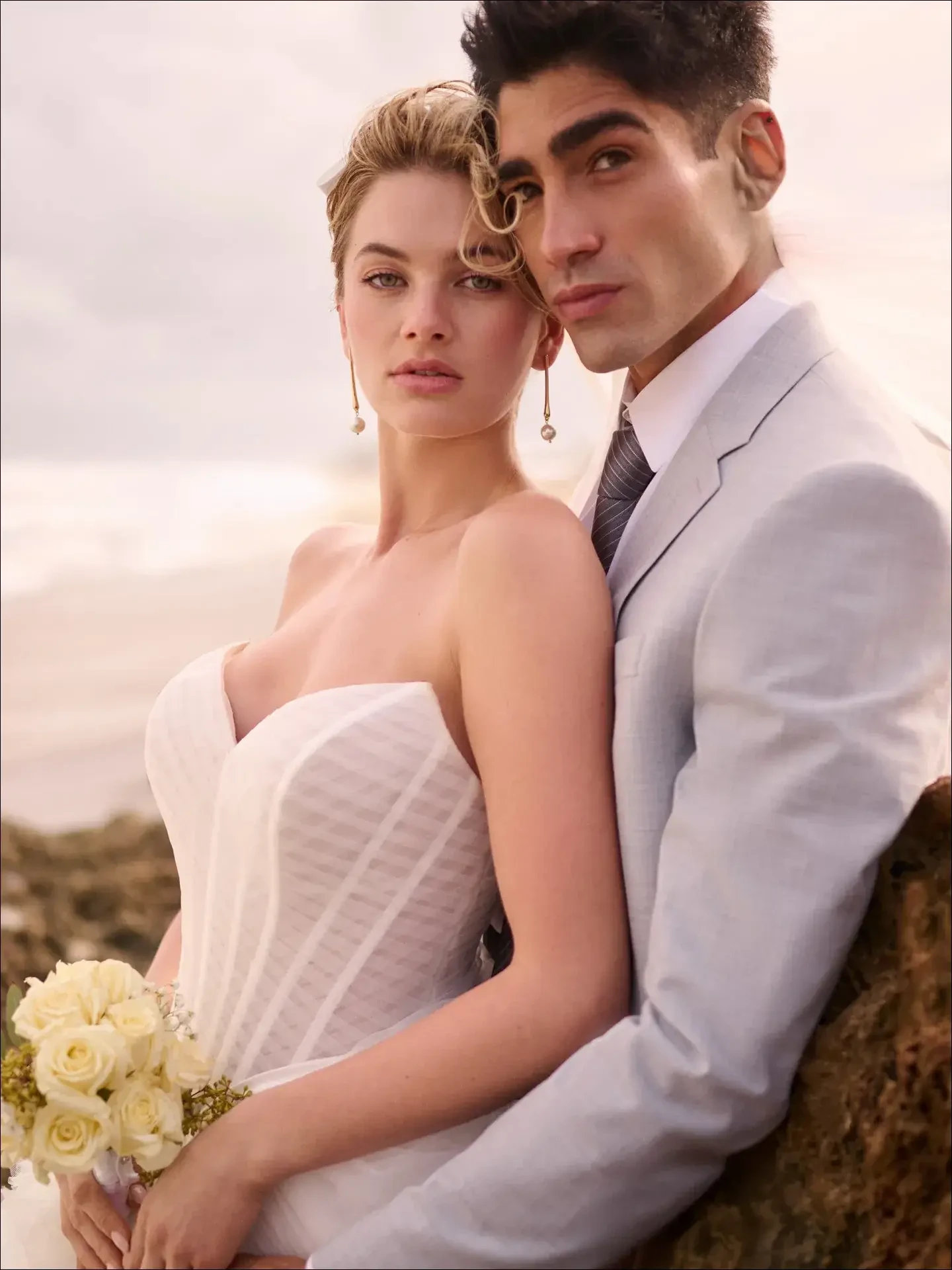 Model is wearing a strapless sweetheart illusion bodice wedding gown with a pleated tulle tiered ballgown skirt, basque waist, side slit, and optional train.